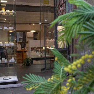 May include: A storefront with a glass display case filled with jewelry. The storefront is located in a narrow alleyway with a brick wall and graffiti art.