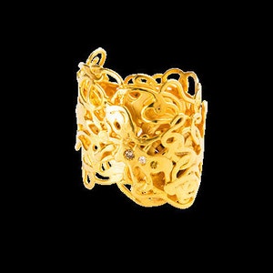May include: A gold ring with a delicate, intricate design. The ring features a swirling pattern with small, clear gemstones.