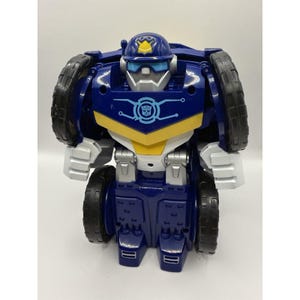 May include: A blue and white robot action figure with black wheels on its shoulders and sides. The robot wears a blue police-style helmet with a yellow badge, features a light blue chest emblem with a central icon, and has silver accents.