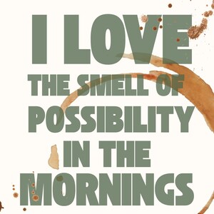 Peut inclure: Fond blanc avec le texte "I LOVE THE SMELL OF POSSIBILITY IN THE MORNINGS" en vert olive. Taches et éclaboussures de café brun sont visibles.