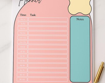 May include: A Daily Planner notepad with a pink and white design. The notepad features sections for time and tasks, with additional areas for today's priorities and notes. A gold pen rests on the side.