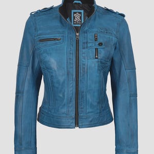 May include: A teal blue leather jacket with a zip-up front, multiple pockets, and a stand-up collar. The jacket has a fitted silhouette and features decorative stitching details. The jacket has a black lining and a small logo patch near the collar.