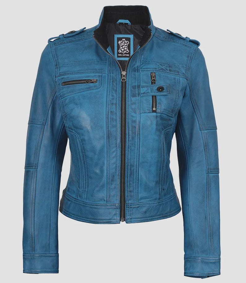 May include: A teal blue leather jacket with a zip-up front, multiple pockets, and a stand-up collar. The jacket has a fitted silhouette and features decorative stitching details. The jacket has a black lining and a small logo patch near the collar.