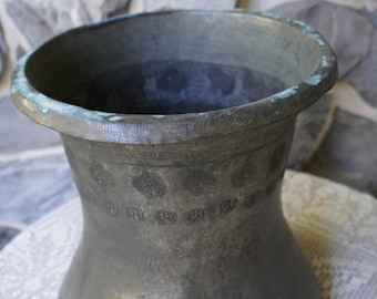 A sturdy antique copper vessel with stamped designs including dahlia coffee pots