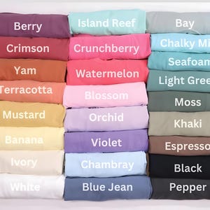 Może przedstawiać: Kolekcja złożonych pr&oacute;bek tkanin w r&oacute;żnych kolorach, w tym Berry, Crimson, Yam, Terracotta, Mustard, Banana, Ivory, White, Island Reef, Crunchberry, Watermelon, Blossom, Orchid, Violet, Chambray, Blue Jean, Bay, Chalky Mint, Seafoam, Light Green, Moss, Khaki, Espresso, Black i Pepper.