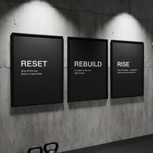 Puede incluir: Tres carteles motivacionales negros enmarcados con texto blanco: "RESET", "REBUILD" y "RISE". Los carteles están montados en una pared gris texturizada. Dos pesas rusas negras están en primer plano. El tema general es el fitness y la superación personal.