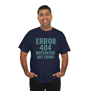 Könnte beinhalten: Marineblaues T-Shirt mit dem Text "ERROR 404 MOTIVATION NOT FOUND" in Türkis. Das T-Shirt hat einen Rundhalsausschnitt. Die Person auf dem Bild trägt das T-Shirt. Der Stoff scheint weich zu sein.