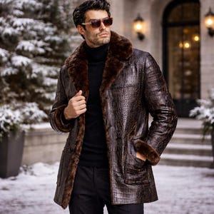 Peut inclure: Un manteau en cuir marron avec un motif crocodile, un col et des poignets en fourrure. Le manteau est boutonné et possède des poches. La personne porte des lunettes de soleil et un col roulé noir. L'arrière-plan montre une scène extérieure enneigée.