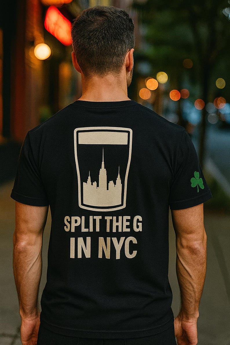 May include: Black t-shirt featuring a white graphic of the New York City skyline within a beer glass shape. The text "SPLIT THE G IN NYC" is below the graphic. A green shamrock is on the sleeve.