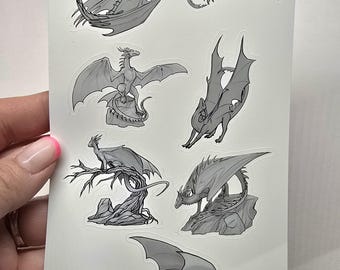 May include: A sheet of stickers featuring seven different black and white illustrations of dragons in various poses. The dragons are drawn in a realistic style with detailed scales and wings.
