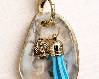 Llavero de ostra con borla azul y dije de velero