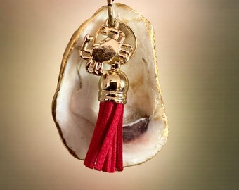 Llavero de ostra con borla roja y dije de cangrejo