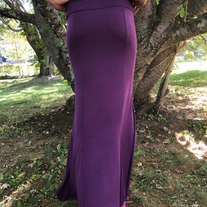 Peut inclure: Une longue jupe violet fonc&eacute;, pr&egrave;s du corps. Elle pr&eacute;sente une large ceinture et s'&eacute;vase l&eacute;g&egrave;rement vers le bas, cr&eacute;ant une silhouette &eacute;l&eacute;gante. Le tissu semble &ecirc;tre une mati&egrave;re douce et extensible, adapt&eacute;e &agrave; diverses occasions.