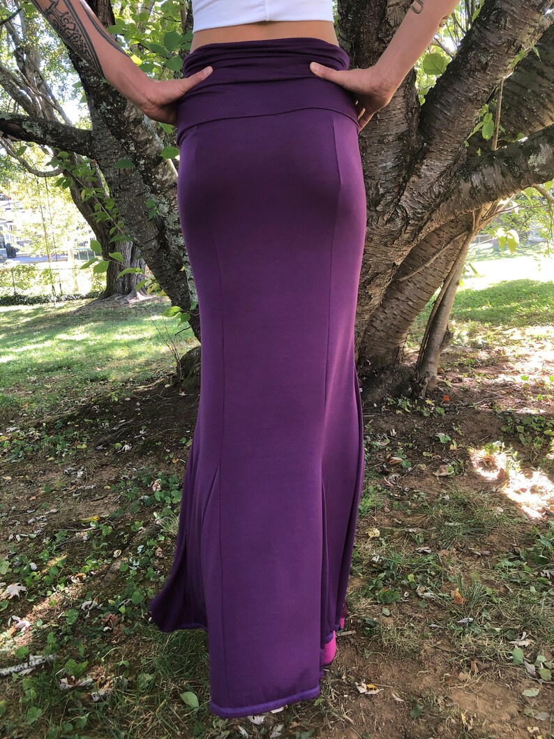 Peut inclure: Une longue jupe violet fonc&eacute;, pr&egrave;s du corps. Elle pr&eacute;sente une large ceinture et s'&eacute;vase l&eacute;g&egrave;rement vers le bas, cr&eacute;ant une silhouette &eacute;l&eacute;gante. Le tissu semble &ecirc;tre une mati&egrave;re douce et extensible, adapt&eacute;e &agrave; diverses occasions.