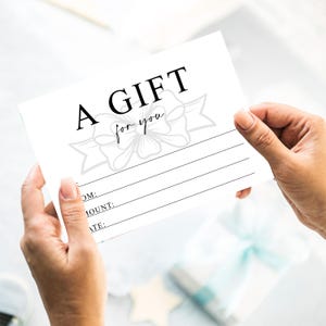 K&ouml;nnte beinhalten: Ein wei&szlig;er Geschenkgutschein mit den Worten "A GIFT for you" in schwarzer Schrift. Der Gutschein hat eine dekorative Schleifengrafik und Linien f&uuml;r Empf&auml;nger, Betrag und Datum. Der Gutschein wird von zwei H&auml;nden gehalten.