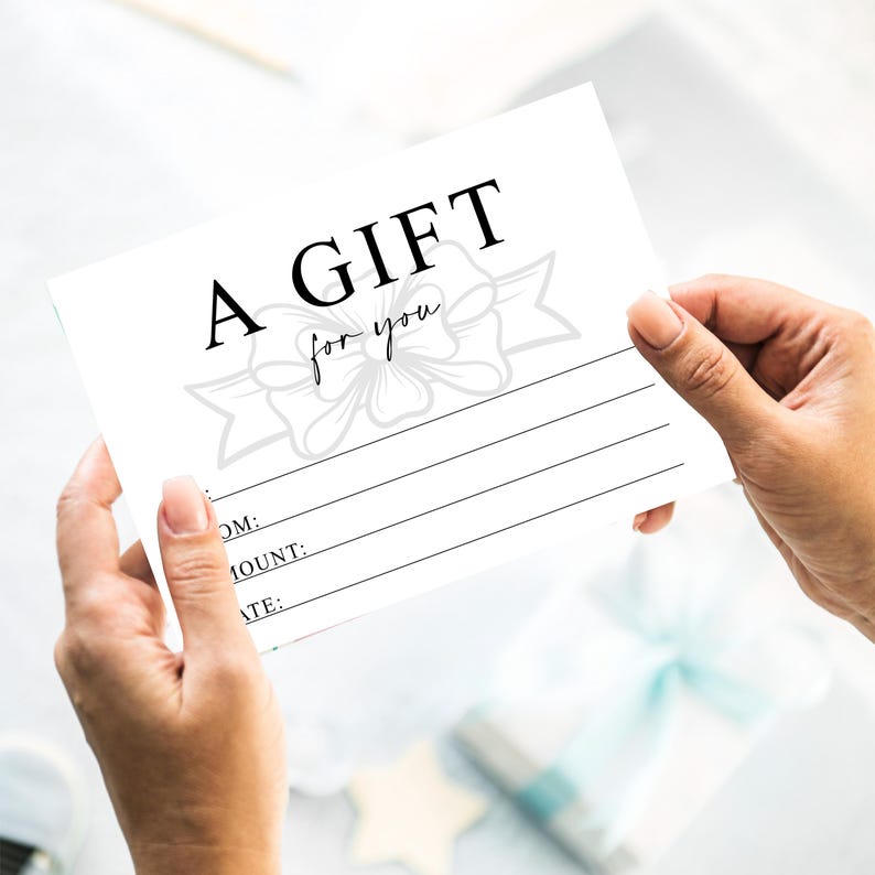 K&ouml;nnte beinhalten: Ein wei&szlig;er Geschenkgutschein mit den Worten "A GIFT for you" in schwarzer Schrift. Der Gutschein hat eine dekorative Schleifengrafik und Linien f&uuml;r Empf&auml;nger, Betrag und Datum. Der Gutschein wird von zwei H&auml;nden gehalten.