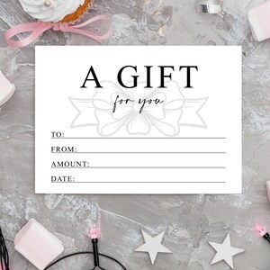K&ouml;nnte beinhalten: Ein wei&szlig;er Geschenkgutschein mit den Worten "A GIFT for you" in schwarzer Schrift. Der Gutschein hat Zeilen f&uuml;r "TO:", "FROM:", "AMOUNT:" und "DATE:". Der Hintergrund ist eine hellgraue, gesprenkelte Oberfl&auml;che.