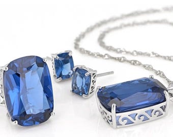 May include: A jewelry set featuring a ring, earrings, and a pendant necklace. The set includes a large, rectangular, deep blue gemstone set in silver-toned metal. The ring and pendant have decorative openwork designs.