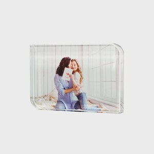 Puede incluir: Un bloque de fotos de acrílico transparente que muestra una fotografía de una mujer y una niña abrazándose. La mujer sostiene una tarjeta con un corazón y la palabra "MOM". La foto está sobre un fondo blanco.
