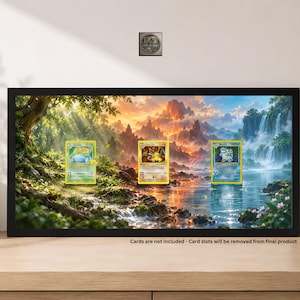 May include: A rectangular black-framed display case featuring a vibrant landscape print of a forest, mountains, and a waterfall. The print includes three rectangular slots for trading cards. Text at the bottom reads: Cards are not included - Card slots will be removed from final product.