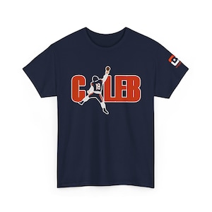 Puede incluir: Camiseta azul marino con el nombre "CALEB" en letras de bloque naranjas con contorno blanco. Una ilustración estilizada de un jugador de fútbol americano lanzando un balón está en el centro. El número del jugador es "18".