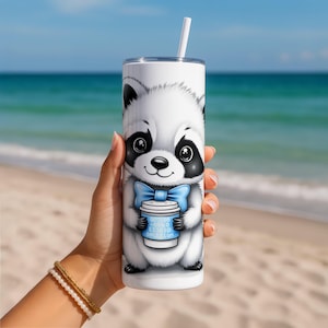 Könnte beinhalten: Ein weißer Becher mit einem Cartoon-Waschbären-Design. Der Waschbär hat schwarz-weißes Fell, eine blaue Fliege und hält einen blauen Kaffeebecher mit Binärcode und dem Wort "operation". Ein weißer Strohhalm steckt im Deckel.