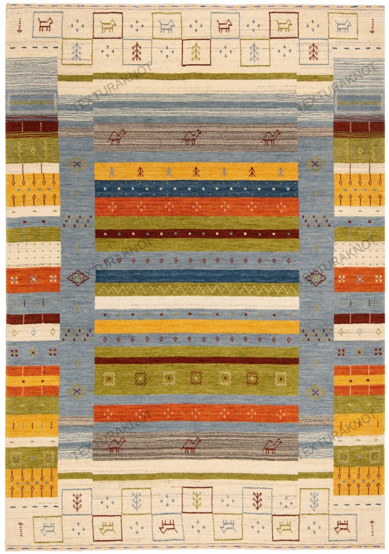 May include: A rectangular rug with a central design of horizontal stripes in blue, orange, yellow, and green. The rug has a cream-colored border with repeating geometric patterns and camel motifs. The rug's dimensions are not visible.