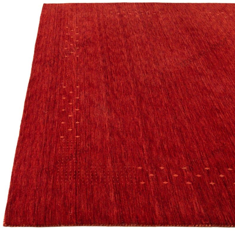 Pu&ograve; includere: Un grande tappeto rosso rettangolare con una superficie strutturata. Il tappeto presenta un sottile motivo di piccoli accenti a forma di diamante lungo i bordi. Il colore del tappeto &egrave; un rosso intenso e caldo, adatto a soggiorni o camere da letto.