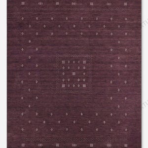 May include: A rectangular, dark burgundy rug with a geometric pattern. The rug features a central square design and borders with repeating diamond and dot patterns in a lighter color. The texture appears woven, suitable for home decor.