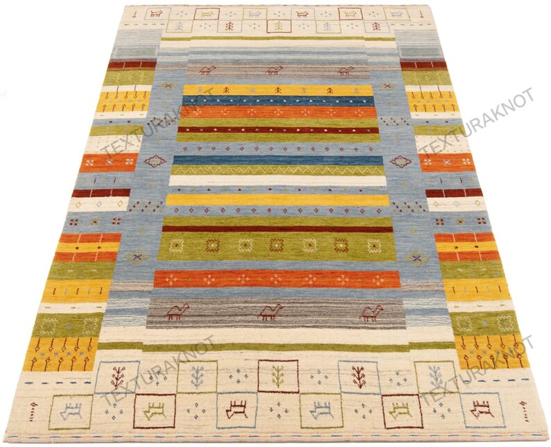 May include: A rectangular area rug with a light blue central field and colorful horizontal stripes in shades of orange, yellow, green, and brown. The rug features geometric patterns and small animal motifs.