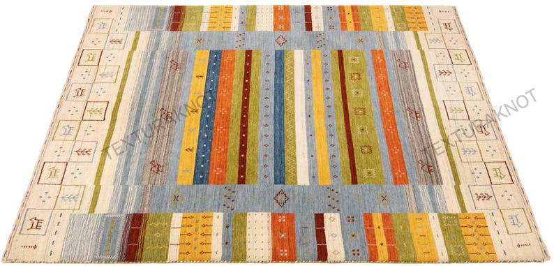 May include: A rectangular area rug with a light blue central field and colorful vertical stripes in orange, yellow, green, and red. The rug has a cream-colored border with geometric patterns and a diamond design.