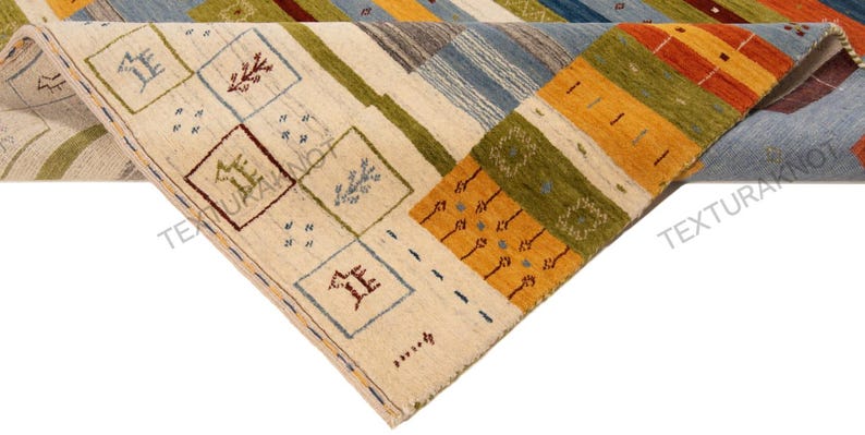 May include: A colorful, geometric area rug with a folded corner. The rug features a cream-colored background with squares and rectangles in shades of blue, green, orange, and brown. The design includes stylized patterns and shapes.