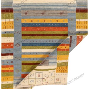 May include: A rectangular, hand-woven rug with a geometric design. The rug features a light beige background with blue, yellow, orange, and green stripes and borders. Decorative animal and tree motifs are incorporated throughout the design.