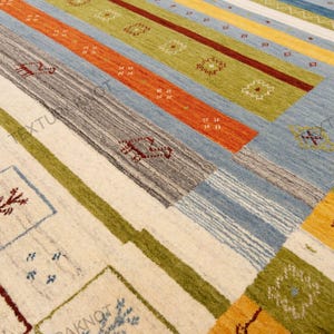 May include: A colorful area rug with a geometric pattern. The rug features stripes in various colors, including orange, blue, green, and yellow. The design incorporates squares and rectangles with decorative motifs. The rug is made of a woven material.