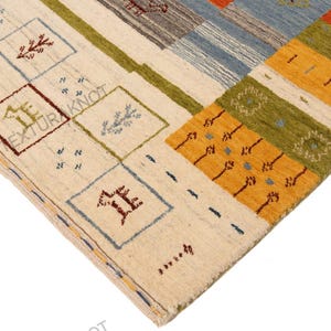 May include: A colorful area rug with a geometric pattern. The rug features squares and rectangles in cream, blue, green, orange, and brown. The design includes stylized plant and geometric shapes.