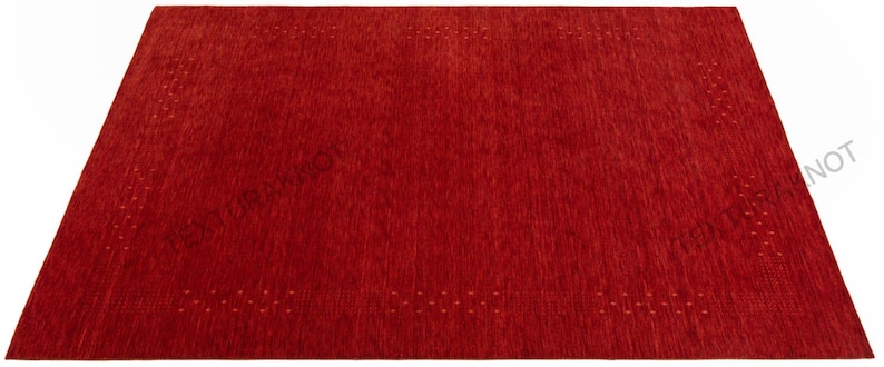 Pu&ograve; includere: Un tappeto rettangolare rosso con una superficie strutturata. Il tappeto ha un campo rosso pieno con un motivo a bordo punteggiato. Il tappeto &egrave; realizzato in un materiale tessuto ed &egrave; adatto per l'arredamento della casa.