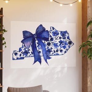 May include: A watercolor painting of the state of Kentucky in blue and white. The state outline is filled with a floral pattern and a large blue bow is centered on the state. The artwork is displayed on a white canvas.