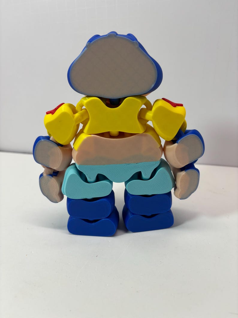 K&ouml;nnte beinhalten: Ein farbenfroher, beweglicher Spielzeugroboter mit blauem Kopf, gelbem Torso und blauen Beinen. Die Arme des Roboters sind gelb mit roten Akzenten. Der Mittelteil ist pfirsichfarben und hellblau. Das Spielzeug ist mit mehreren Gelenken versehen.