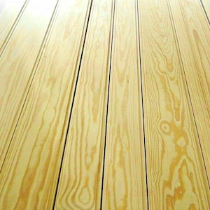 May include: Close-up of light-colored wooden planks with visible grain patterns. The planks are arranged vertically, creating a textured surface. The wood has a natural, warm tone, with subtle variations in color.