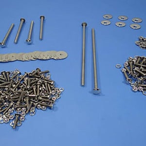 May include: An assortment of silver-colored hardware components, including bolts, washers, and nuts, are arranged on a blue surface. The hardware varies in size and shape, suitable for construction or repair projects.