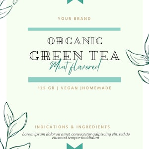 May include: A green and white label for organic green tea with mint flavour. The label features a green ribbon, leafy illustrations, and the text "ORGANIC GREEN TEA Mint flavoured 125 GR | VEGAN | HOMEMADE". The label also includes the text "INDICATIONS & INGREDIENTS Lorem ipsum dolor sit amet, consectetur adipiscing elit, sed do eiusmod tempor incididunt" and a social media icon with the text "@SOCIALNAME".
