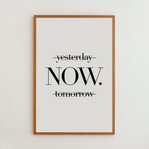 May include: A framed wall art print featuring a light gray background with black text. The word "yesterday" is crossed out with a horizontal line, the word "NOW." is printed in large bold letters, and "tomorrow" is crossed out with a line.