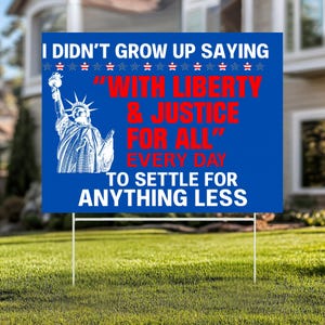 May include: A blue yard sign with white text and a graphic of the Statue of Liberty. The sign reads "I DIDN'T GROW UP SAYING...WITH LIBERTY & JUSTICE FOR ALL...TO SETTLE FOR ANYTHING LESS."