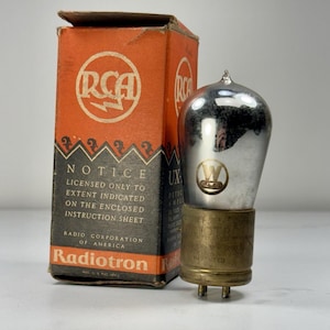 May include: A vintage RCA Radiotron valve with a silver and brass base, beside its original orange and black box. The box displays the RCA logo and the text: "NOTICE LICENSED ONLY TO EXTENT INDICATED ON THE ENCLOSED INSTRUCTION SHEET."