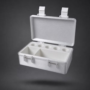 Könnte beinhalten: Eine weiße, rechteckige Aufbewahrungsbox mit Klappdeckel und zwei vorderen Verschlüssen. Das Innere verfügt über ein glattes weißes Fach mit fünf kreisförmigen Vertiefungen an der Rückseite und zwei größeren offenen Fächern im vorderen Bereich.