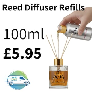 May include: A clear glass reed diffuser bottle with a gold cap is being refilled with a liquid from a silver bottle. The text "Reed Diffuser Refills" and "100ml" are visible. The silver bottle is labeled "Black Cherry".