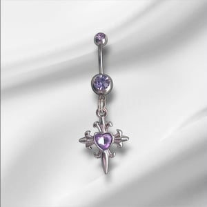 May include: A silver belly button ring with a dangling cross pendant. The cross features a heart-shaped purple gem in the center and fleur-de-lis accents. The ring has two purple gems, one at the top and one in the center.