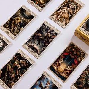 May include: A collection of tarot cards with detailed illustrations and titles like "The Empress," "The Devil," and "Strength." The cards are arranged on a white surface, with a matching box visible. The artwork features rich colors and intricate designs.