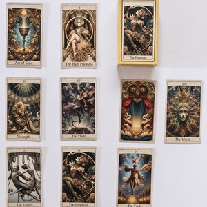 May include: A collection of tarot cards featuring intricate illustrations and text. The cards display images of "Ace of Cups", "The High Priestess", "The Empress", "Strength", "The Devil", "The World", "The Lovers", and "The Fool". The cards are in a box labeled "The Empress".