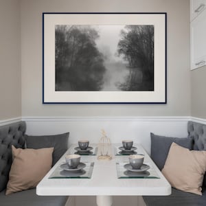 May include: A dining nook featuring a framed black and white landscape photograph above a white table set for four. Gray tufted benches and pillows in gray and beige complete the cozy setting. Four place settings with gray cups and saucers are visible.